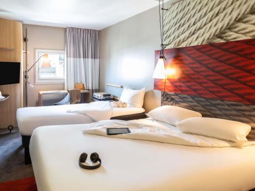 a hotel room with two beds and a tv at Ibis Marne la Vallée Noisy in Noisy-le-Grand