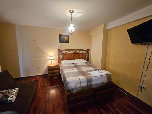 a bedroom with a bed and a couch and a tv at El Seminario Hospedaje in Cajamarca