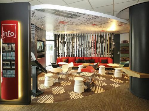 a store with a red couch and tables and chairs at Ibis Marne la Vallée Noisy in Noisy-le-Grand