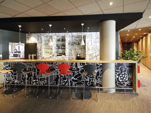 a bar in a lobby with a wall covered in graffiti at Ibis Marne la Vallée Noisy in Noisy-le-Grand