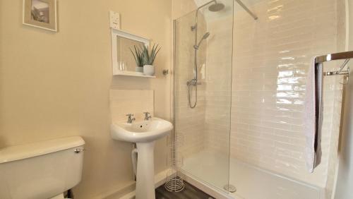 ein weißes Badezimmer mit Waschbecken und Dusche in der Unterkunft Sunrise Cottage in Llanddulas