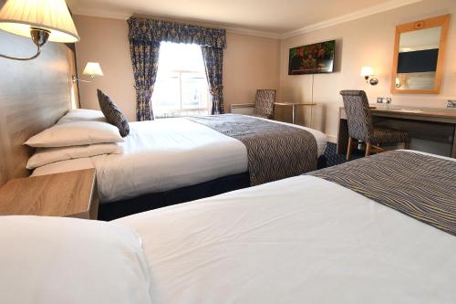 a hotel room with two beds and a desk at The Queens Hotel & Victoria Cloisters Apartments in York
