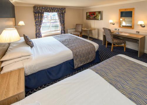 a hotel room with two beds and a desk at The Queens Hotel & Victoria Cloisters Apartments in York