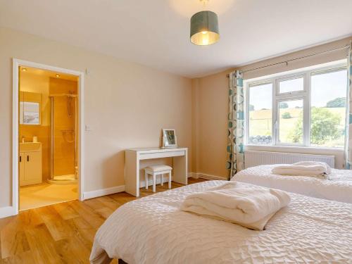 a bedroom with two beds and a desk and a window at 4 Bed in Alsop-En-Le-Dale 88935 in Alsop en le Dale