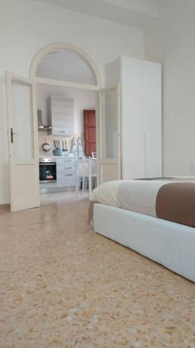 a white bedroom with a bed and a kitchen at Vivi in una Torre Medioevale appartamento in Perugia