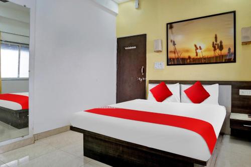 a bedroom with a large bed with red pillows at Super Hotel O Pimpri Stays in Chinchiwad