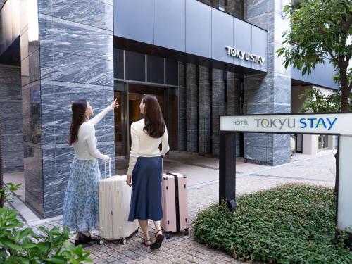 two women standing in front of a building with suitcases at Tokyu Stay Aoyama Premier in Tokyo