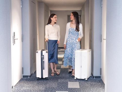 two women standing in a hallway with luggage at Tokyu Stay Aoyama Premier in Tokyo