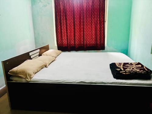 デーオーガルにあるAlkapuri Guest Houseの赤いカーテンが付いた部屋のベッド1台