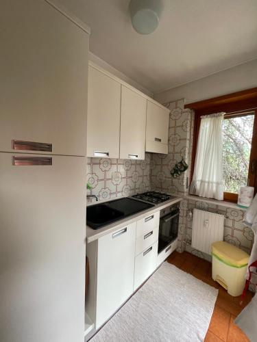 a kitchen with white cabinets and a stove top oven at Ampio appartamento per 8 a due passi dal centro in Bardonecchia