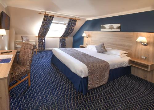 a hotel room with a large bed and a desk at The Queens Hotel & Victoria Cloisters Apartments in York