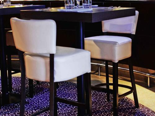 two white bar stools at a table in a restaurant at Mercure Chambéry Centre in Chambéry