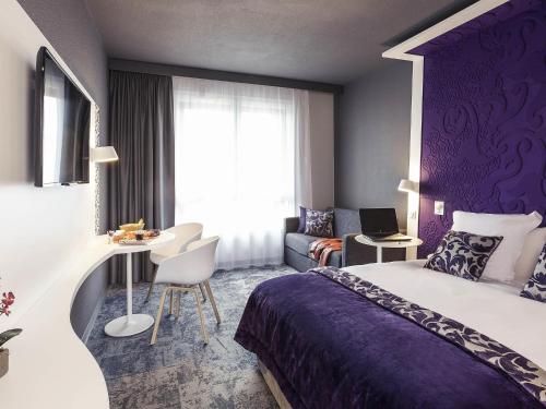 a hotel room with a large bed and a table at Mercure La Roche Sur Yon in La Roche-sur-Yon