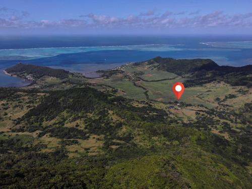 a red balloon flying over a mountain with the ocean at Le Chalet, at La Petite Ferme in Vieux Grand Port