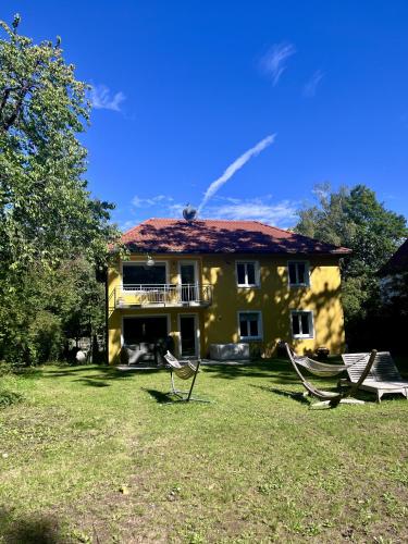 a yellow house with two chairs in the yard at Large Munich house with 4 bedrooms in a quiet and greened villa area near Munich in Munich