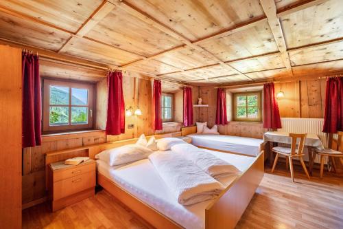 a bedroom with two beds in a room with red curtains at Unterlacherhof Ahrntal in San Giacomo
