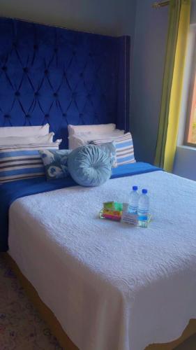 a bed with a blue headboard and bottles of water on it at Tubungu- House of Lux& Lush in Matsapha