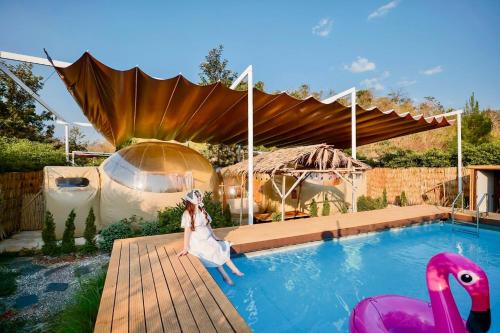 a woman in a white dress sitting in a swimming pool at The X10 Nordic Tent and Glamping Pool Villa Khaoyai เขาใหญ่ - SHA Certified in Ban Thung Sawang