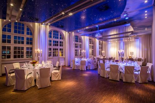 a banquet hall with white tables and white chairs at Mintrops Stadt Hotel Margarethenhöhe in Essen