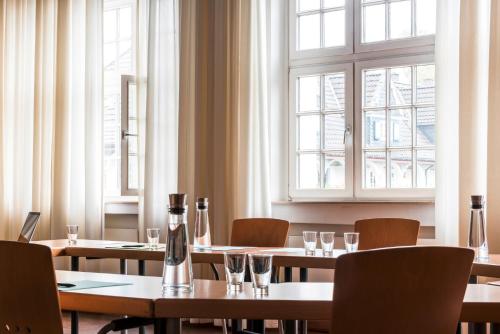 a dining room with tables and chairs and windows at Mintrops Stadt Hotel Margarethenhöhe in Essen