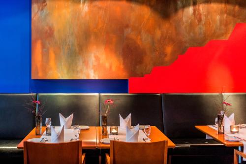 a dining room with tables and chairs and a painting at Mintrops Stadt Hotel Margarethenhöhe in Essen