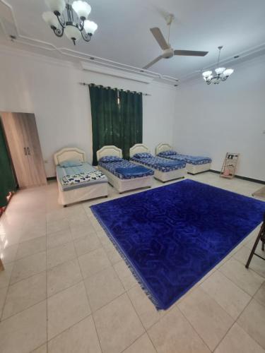 MawāliḩにあるAzarakhsh hostelのベッドが4つと青いラグが敷かれた部屋