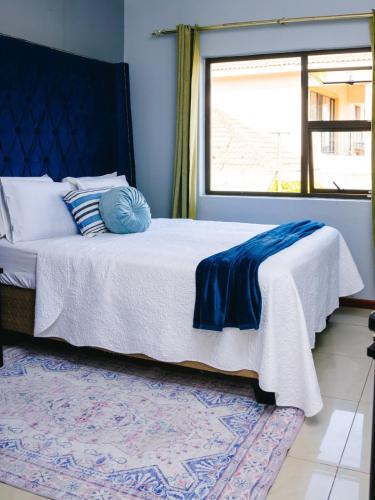 a bedroom with a bed with a blue headboard and a window at Tubungu- House of Lux& Lush in Matsapha