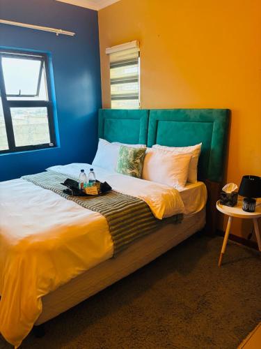 a large bed with a green headboard in a room at Tubungu- House of Lux& Lush in Matsapha