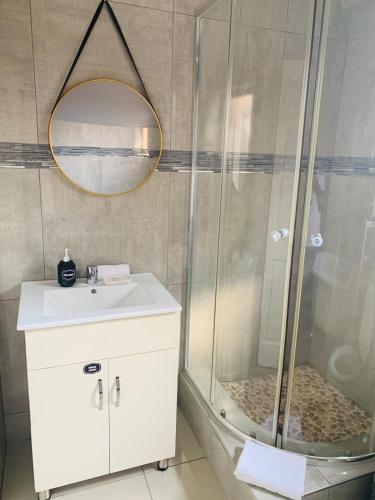 a bathroom with a shower and a sink and a mirror at Tubungu- House of Lux& Lush in Matsapha
