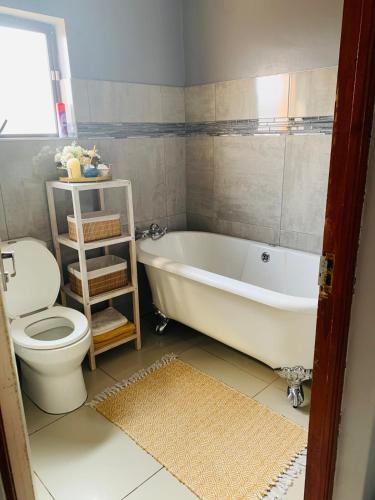 a bathroom with a white tub and a toilet at Tubungu- House of Lux& Lush in Matsapha