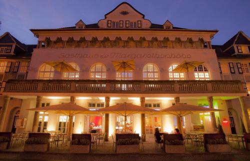 a building with tables and umbrellas in front of it at Mintrops Stadt Hotel Margarethenhöhe in Essen