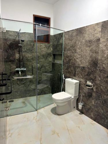a bathroom with a toilet and a glass shower at Niyanca Guest in Beruwala