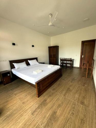 a bedroom with a large bed and a wooden floor at Niyanca Guest in Beruwala