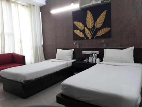 a hotel room with two beds and a red chair at Hotel tathagat bodhgaya near main temple in Bodh Gaya