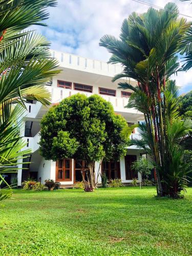 a white building with palm trees in front of it at Niyanca Guest in Beruwala