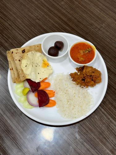 Un plato blanco de comida con arroz y otros alimentos. en Staycation Buddy's Piyush Villas, en Chinchavli