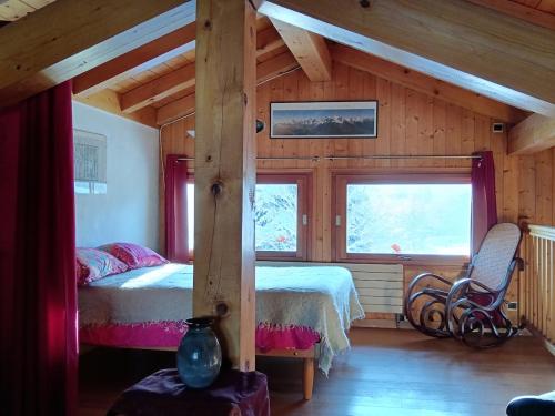 a bedroom in a log cabin with a bed and two windows at Le chalet de Julbert in Combloux