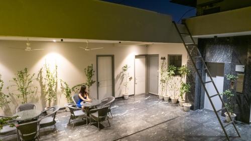 a woman sitting at a table on a patio at Lime Tree Hotel & Stays Greater Noida Nearby India Expo Centre & Mart in Greater Noida