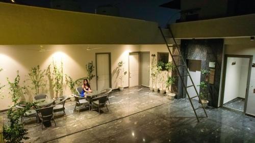 a woman sitting at a table in a room with plants at Lime Tree Hotel & Stays Greater Noida Nearby India Expo Centre & Mart in Greater Noida