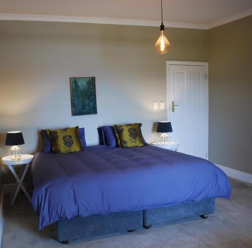 a bedroom with a large blue bed with two tables at Essio's Garden Apartment, Simons Town South Africa in Simonʼs Town