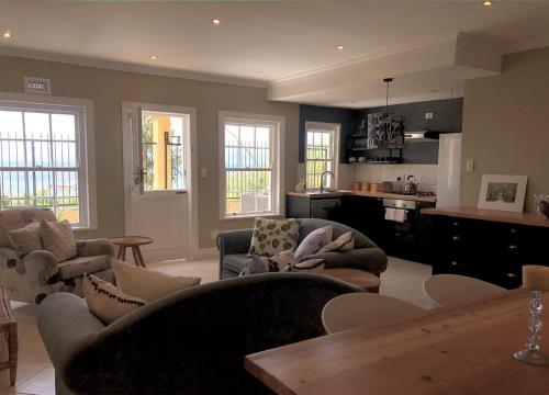 a living room with couches and chairs and a kitchen at Essio's Garden Apartment, Simons Town South Africa in Simonʼs Town