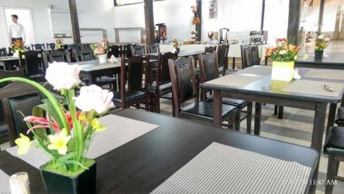 a dining room with tables and chairs and flowers at Hotel Evia in Eforie Nord