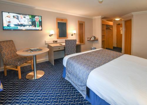 a hotel room with a bed and a desk and a table at The Queens Hotel & Victoria Cloisters Apartments in York