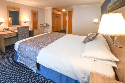 a hotel room with a large bed and a desk at The Queens Hotel & Victoria Cloisters Apartments in York