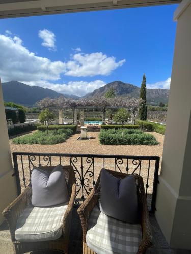 two wicker chairs on a balcony with a view at Auberge Clermont in Franschhoek