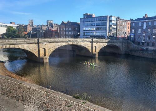 a bridge over a river with a group of people kayaking at The Queens Hotel & Victoria Cloisters Apartments in York