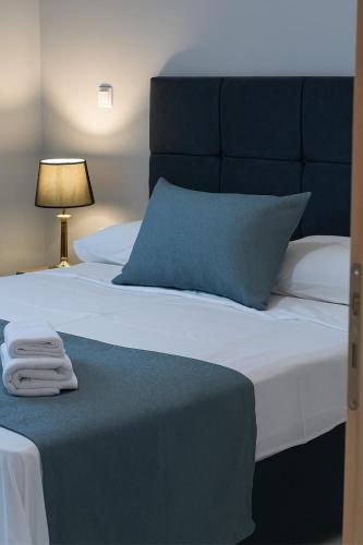 a bed with a blue pillow and a table with a lamp at Chios Cozy Apartment 3 in Sklaviá