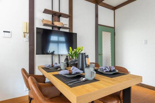 a dining room table with chairs and a television at Shinjuku 24mins train 4BR 8 Beds 2BA in Chofu