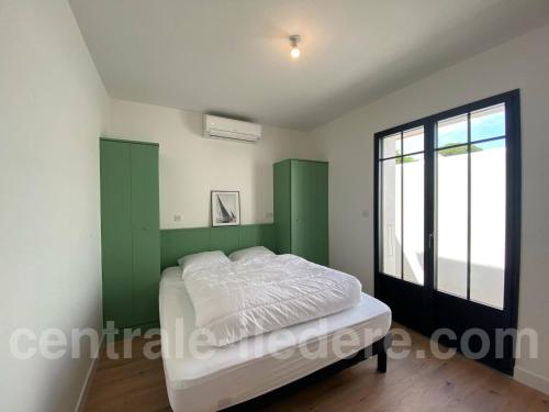 un dormitorio con una cama y una ventana en La Villa Alamy, en Le Bois-Plage-en-Ré