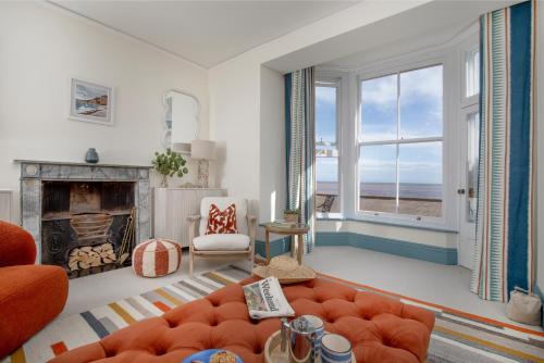 a living room with an orange couch and a fireplace at Admirals Hard in Budleigh Salterton